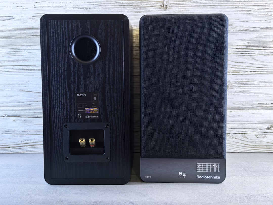 Two black bookshelf speakers photographed from the front and back against a white background