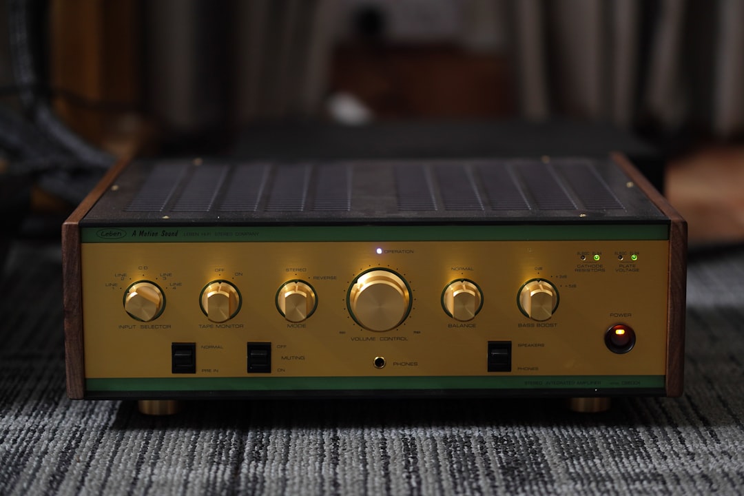 Vintage audio amplifier with gold knobs and wooden trim on a shelf